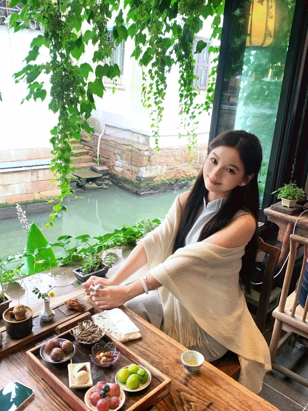 女性坐在有绿植的窗边座位